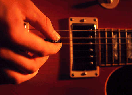 [Billede: Hånd med plektor. Spiller på guitar.]