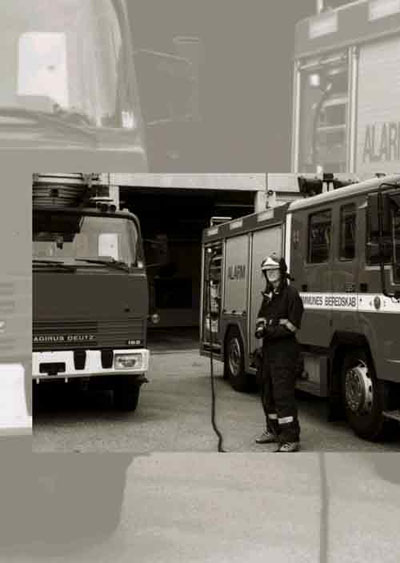 [Billede: En brandmand, som står mellem to brandbiler]