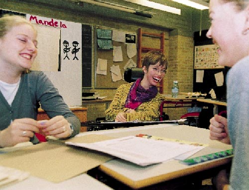 [Billede: Billedet er taget i et klasselokale. Man ser tre grinende elever, der sidder samlet omkring et bord.]