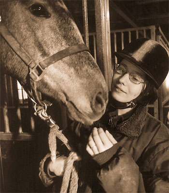 [Billede: Her ses en pige, der står ude i en stald sammen med en hest.]