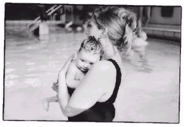 [Billede: En kvinde med en baby på armen, går i et lavt svømmebassin]