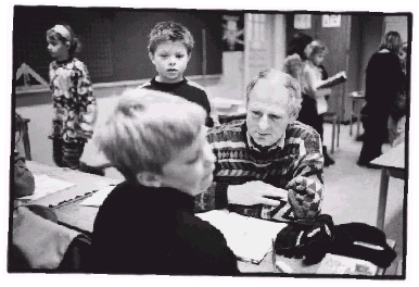 [Billede: Lærer og elever snakker ved et bord]