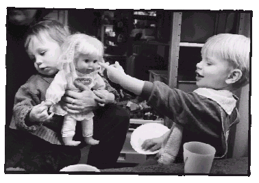 [Billede: To børn leger med en dukke]