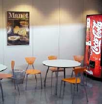 [Billede: Her ses nogle stole og borde foran en Cola automat.]