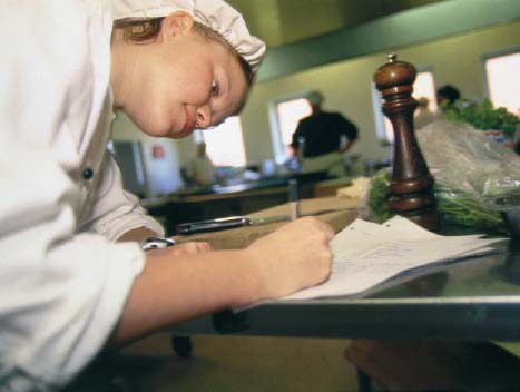 [Billede: Her ses en elev i et køkken, som står og skriver.]
