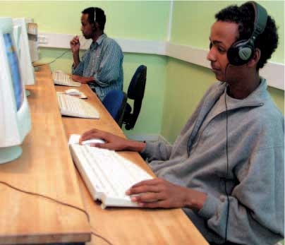 To unge somaliske indvandrermænd sidder foran computeren med hovedtelefoner på hovedet